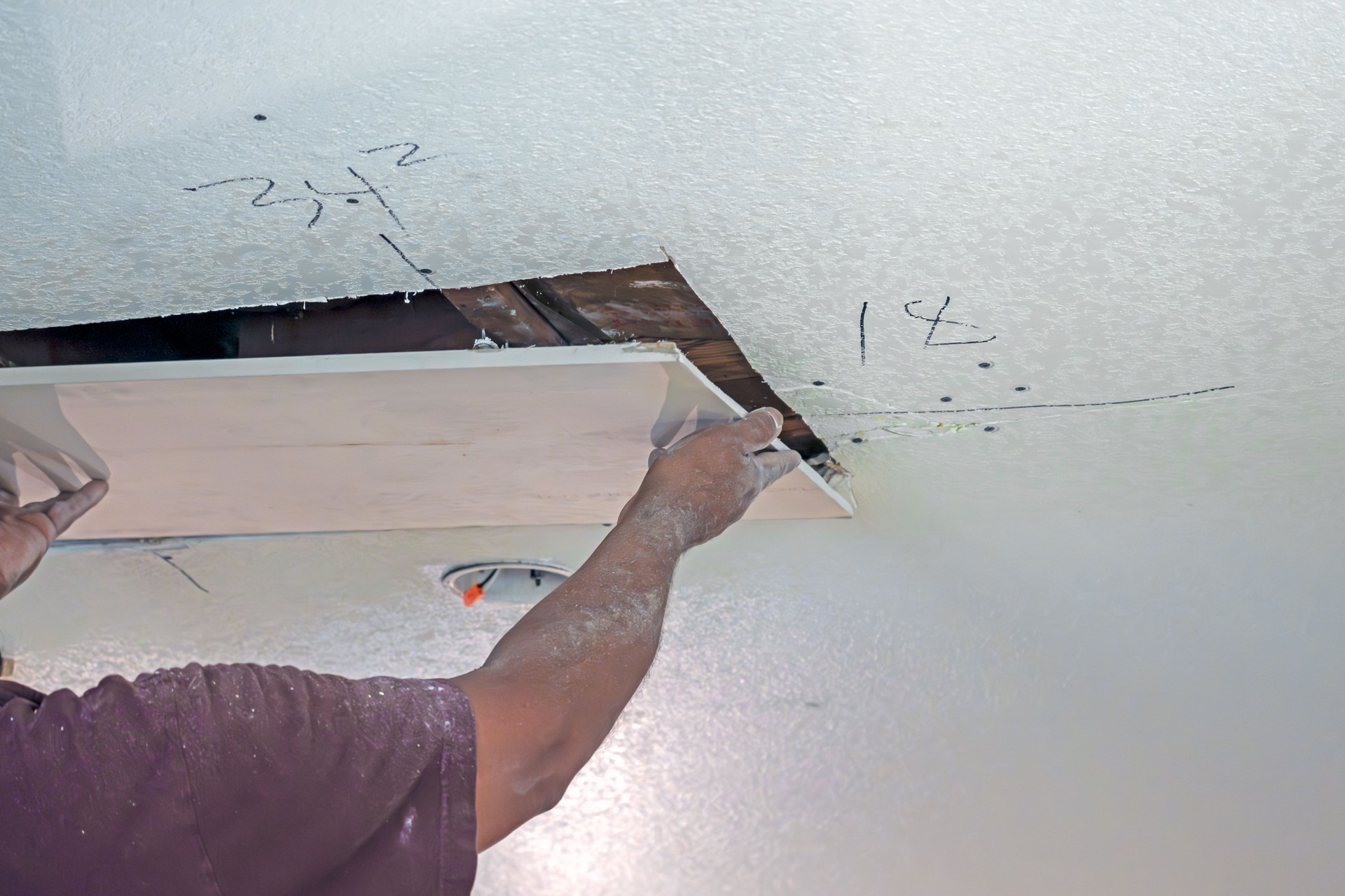 Man replacing or repairing dry wall or sheet rock on a ceiling.