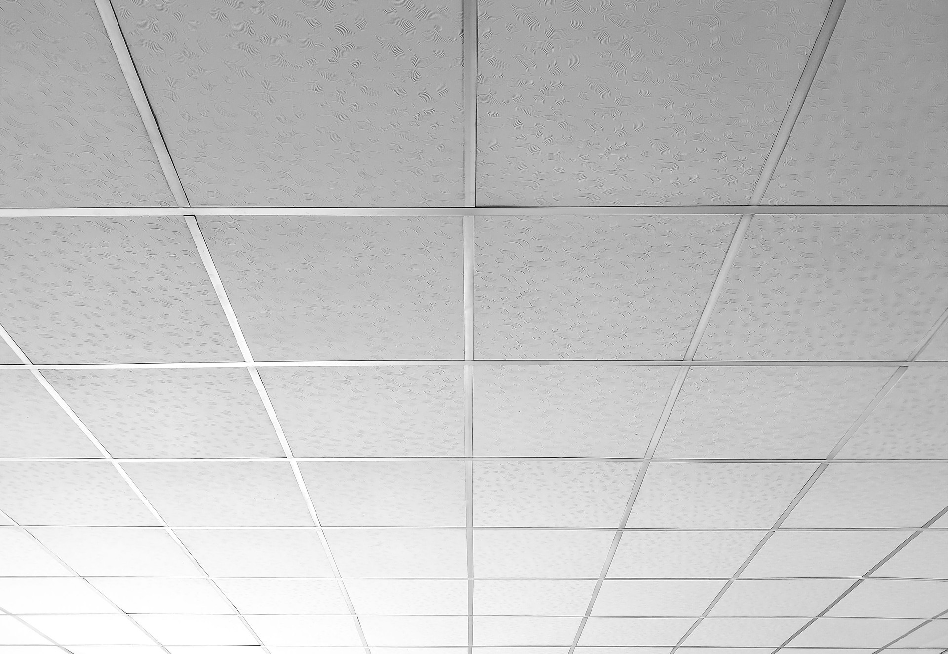 Background and texture of white T bar ceiling tiles with nice light gradation in low angle and perspective view